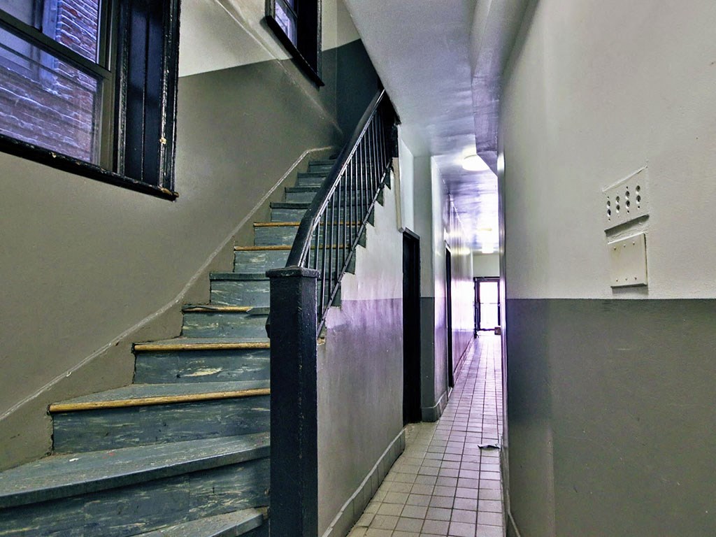 a long hallway with stairs next to a wall and a door
