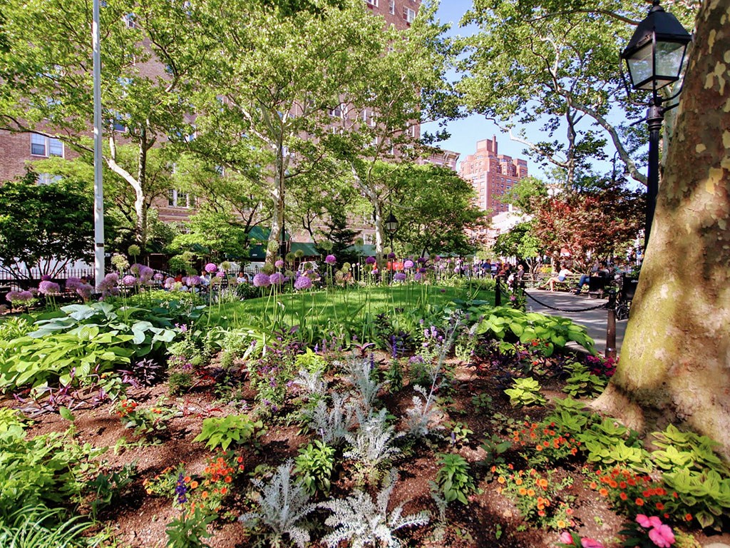 a garden with flowers and trees in a park