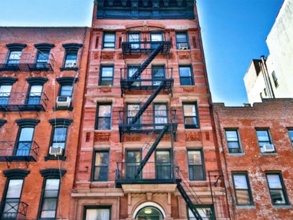 the facade of a tall brick building with fire escapes