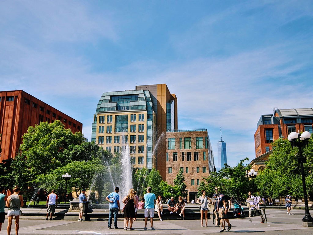 people standing around a fountain in a city square