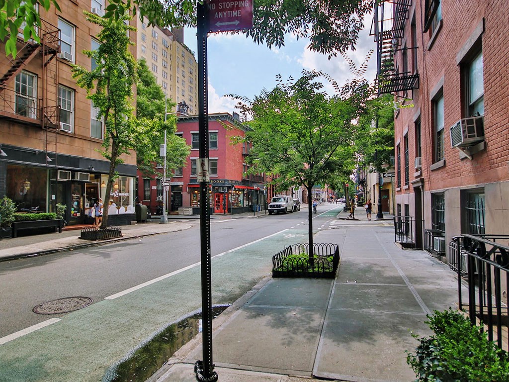 a city street with buildings and trees and a street sign