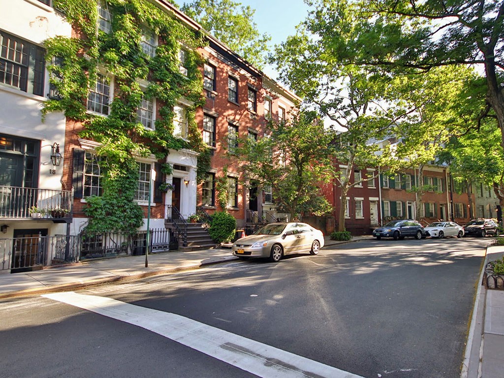 a city street with a car parked in front of a row of houses