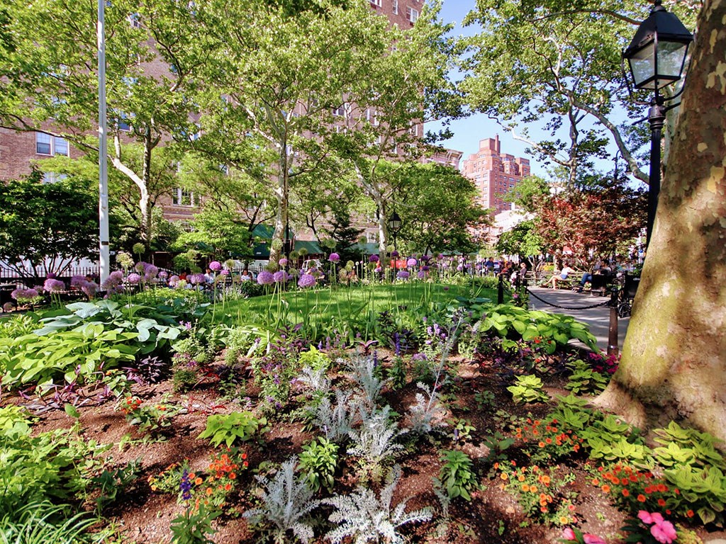 a garden with flowers and trees in a park