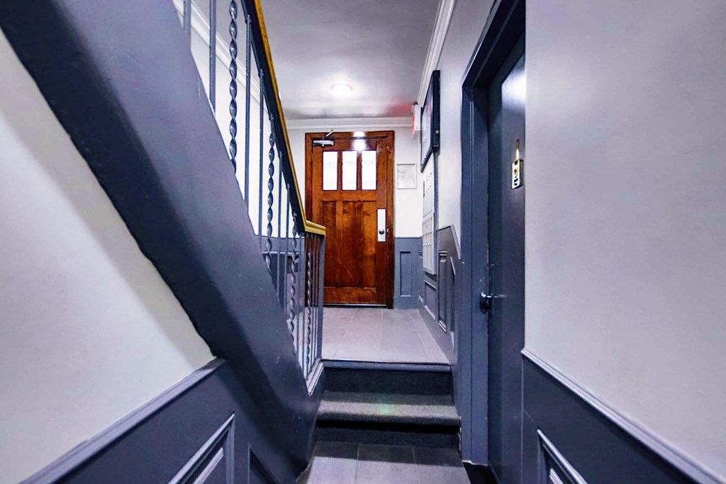 a view from the bottom of a staircase looking into a hallway with a wooden door