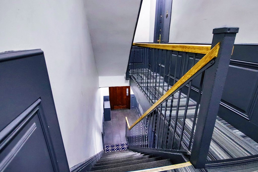 a view down the stairs of a building with a yellow railing and a black staircase