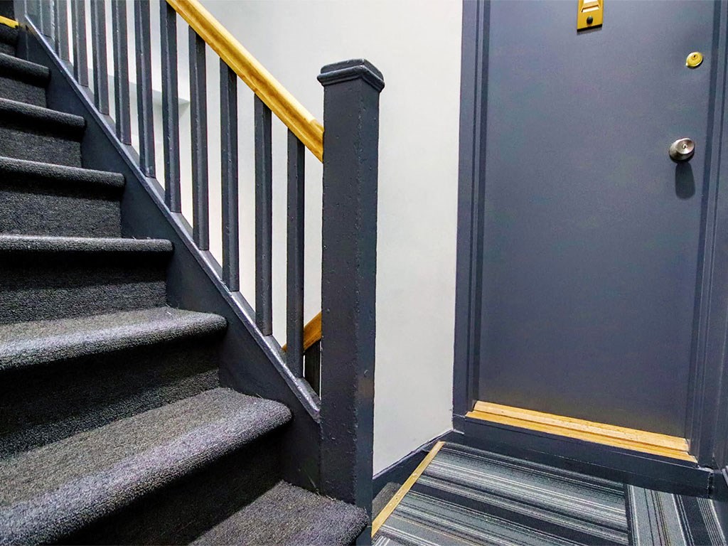 a stairwell with a black door and stairs with a railing and