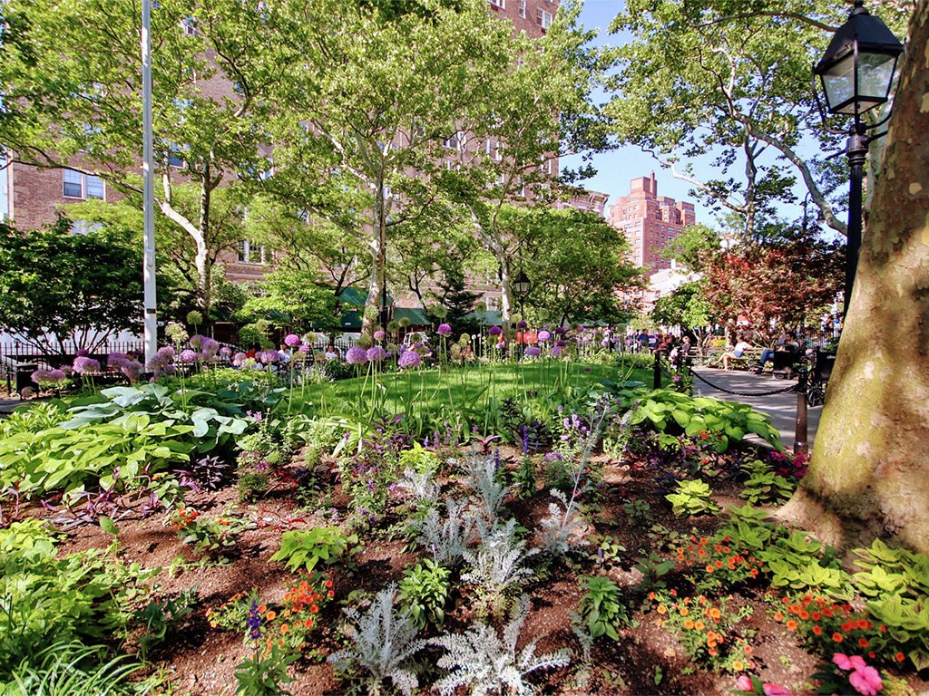 a garden with flowers and trees in a park