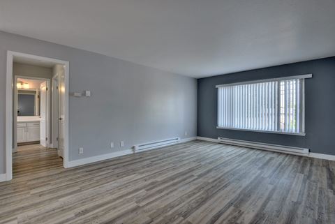 the living room of an empty apartment with wood flooring and a large window