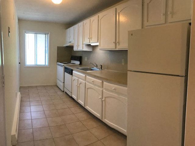 a kitchen with white cabinets and a sink and a refrigerator