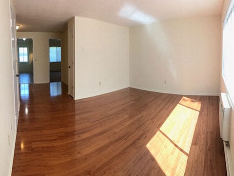 an empty living room with wooden floors and white walls
