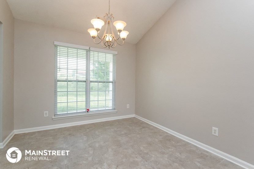 the spacious living room of a home with a large window