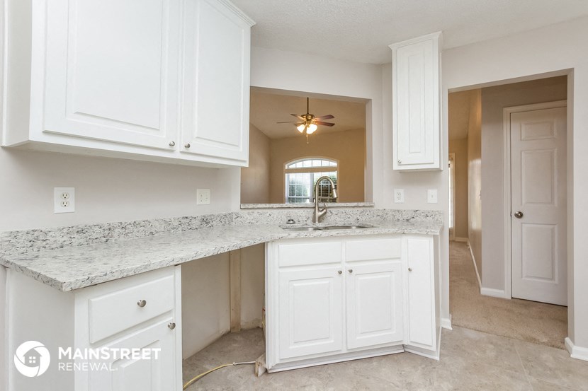 a kitchen with white cabinets and a sink and a counter top