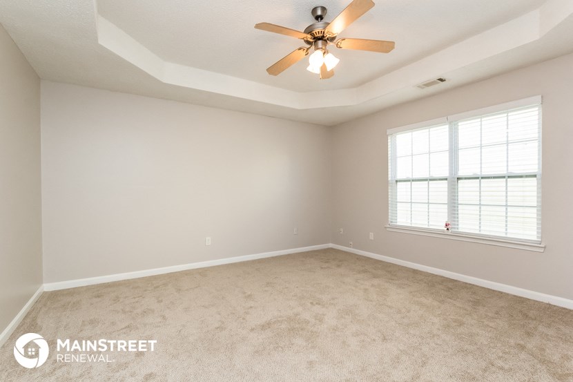 the spacious living room with carpeting and a ceiling fan