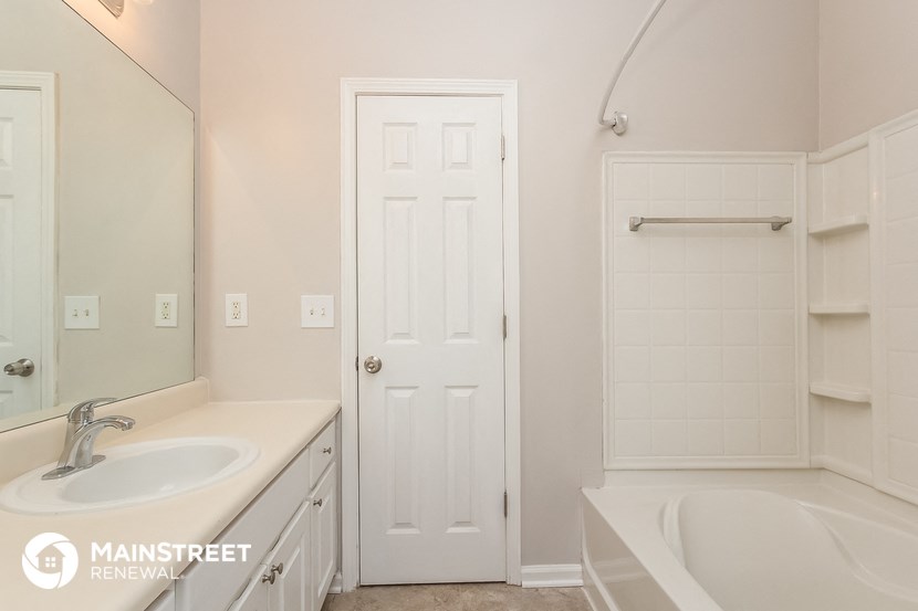 a bathroom with a sink and a shower and a white door