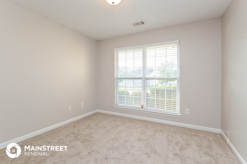 the spacious living room with a large window and carpeting