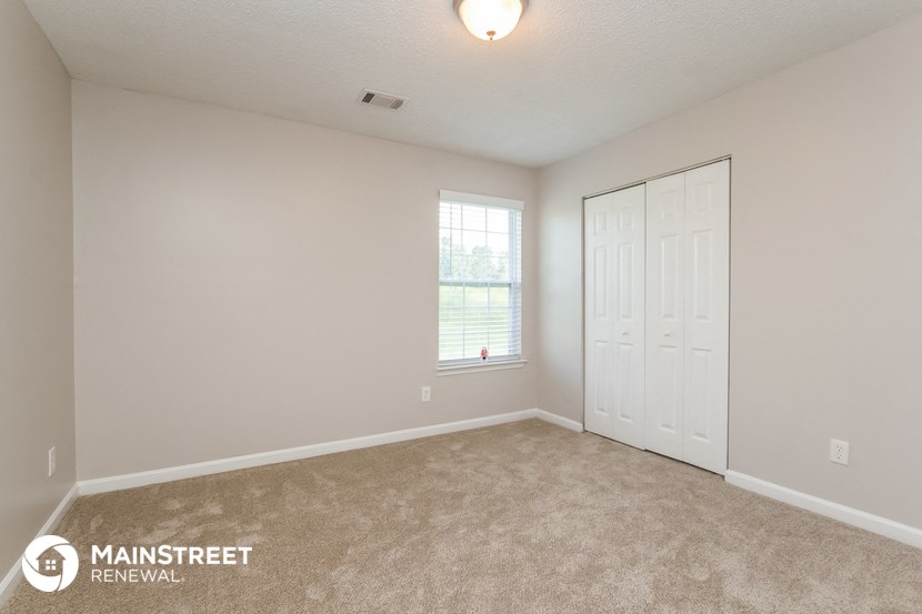the spacious living room with carpeting and a window
