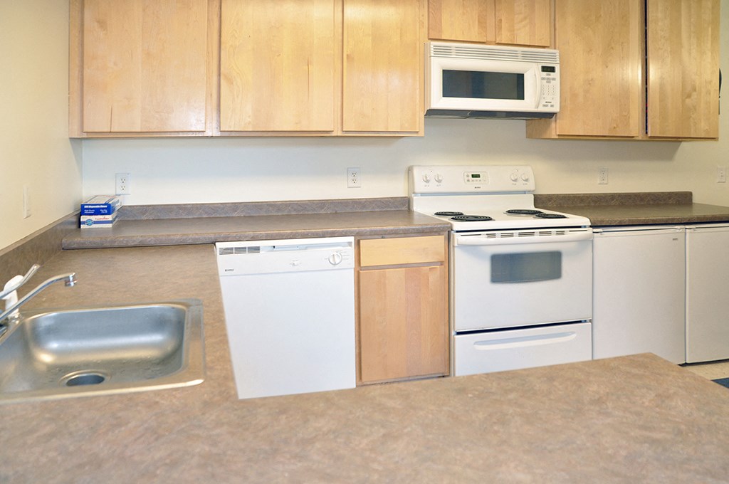 an empty kitchen with white appliances and wooden cabinets