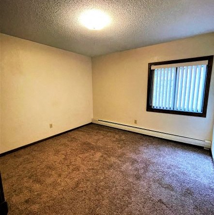an empty living room with a window and carpet