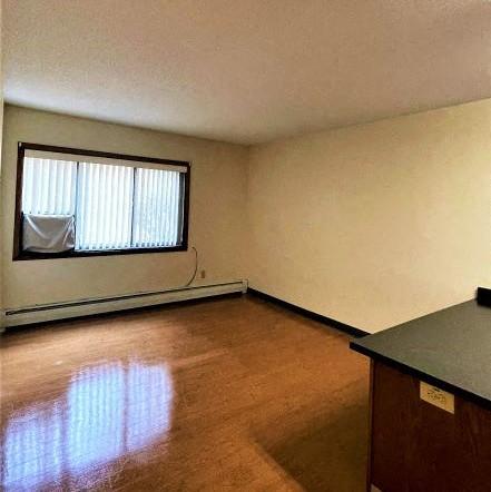 an empty living room with a window and wooden floors