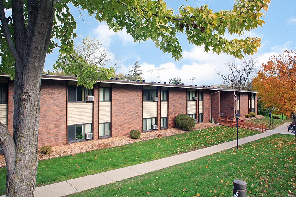 an exterior view of a brick building with green grass and a sidewalk
