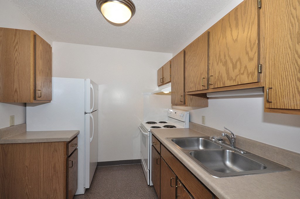 an empty kitchen with a sink and a refrigerator