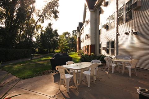 a patio with tables and chairs in front of a house