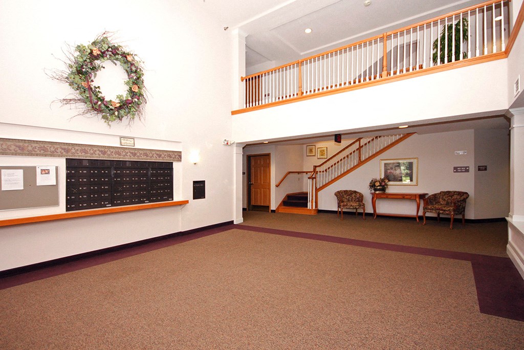 the lobby of a hall with a staircase and a bulletin board