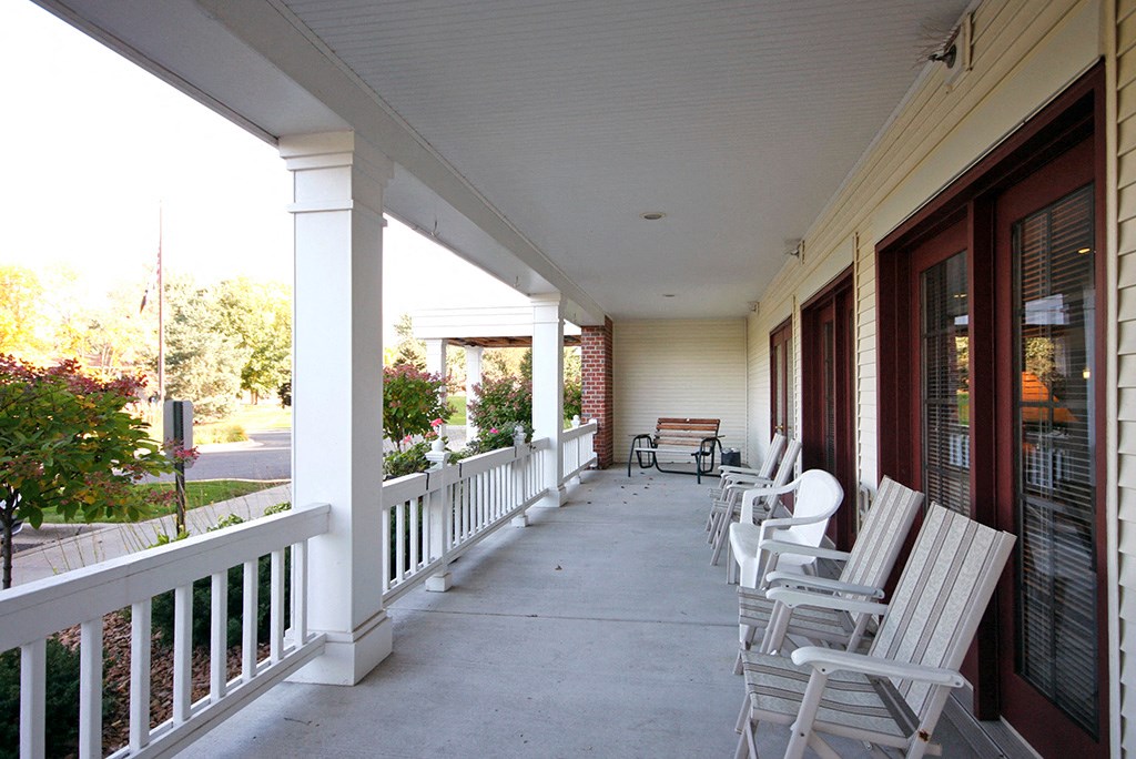 a porch with white rocking chairs and a white house