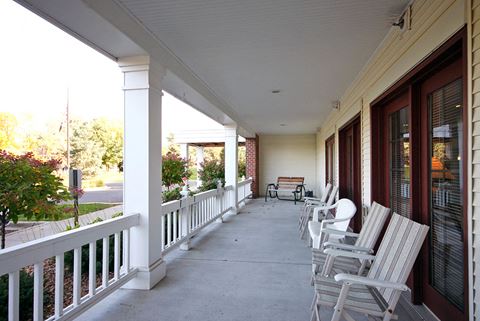 a porch with white rocking chairs and a white house