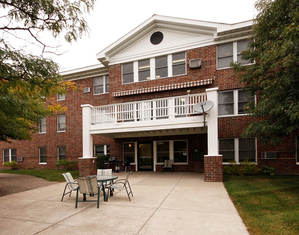 a patio in front of a brick building with tables and chairs