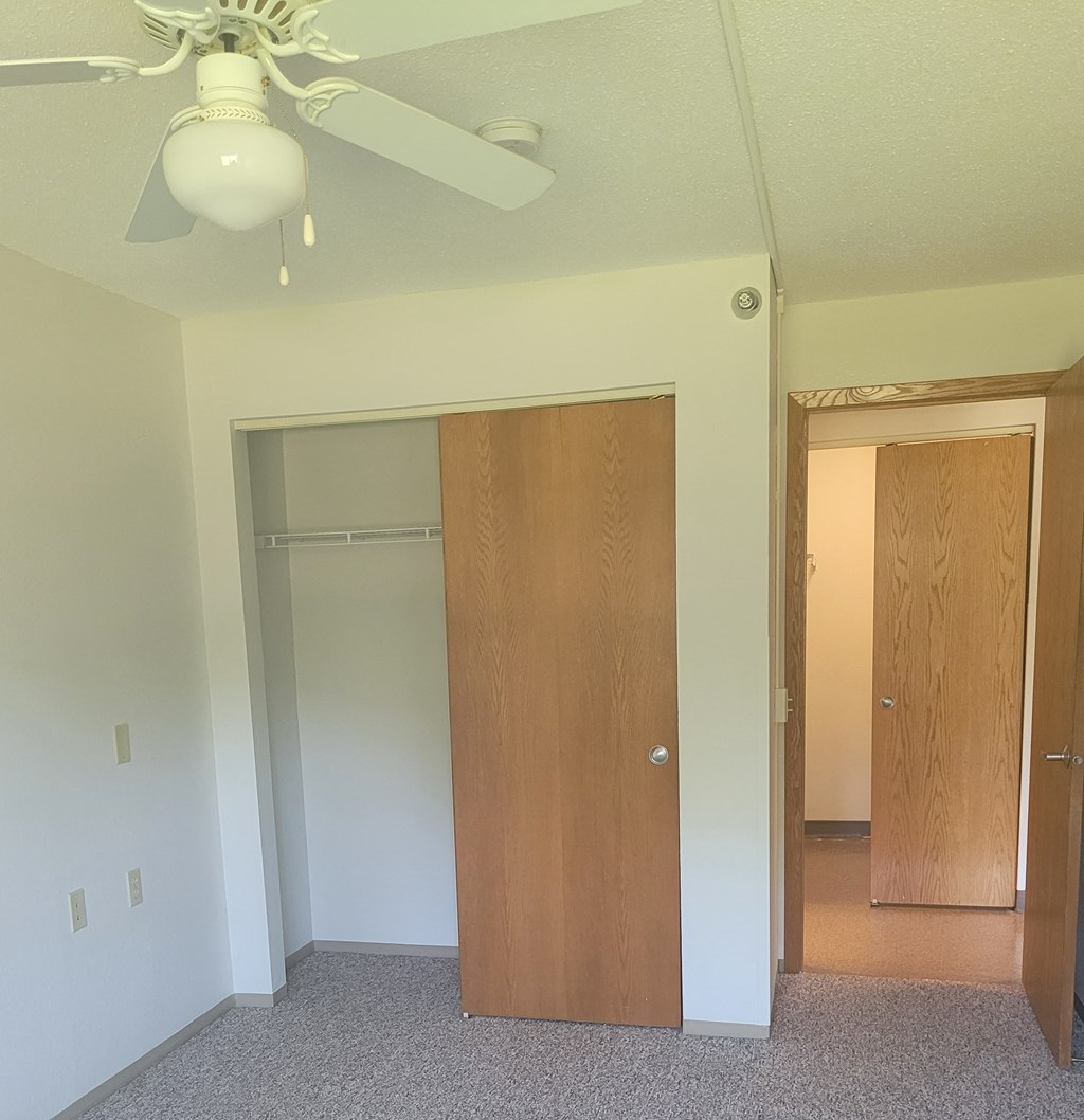 a bedroom with a closet and a ceiling fan