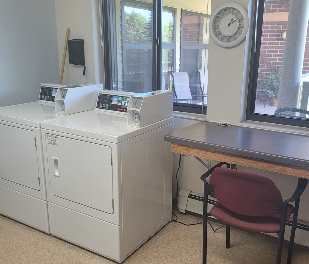 a laundry room with two washing machines and a table with a chair