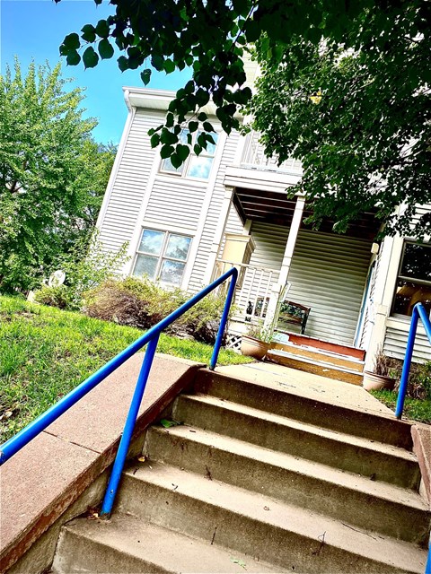 a white house with stairs and a blue railing