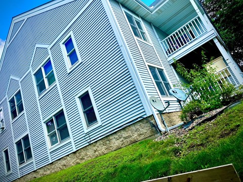 a blue house with white siding and a yard