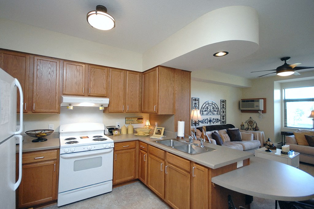 a kitchen with wooden cabinets and white appliances and a living room