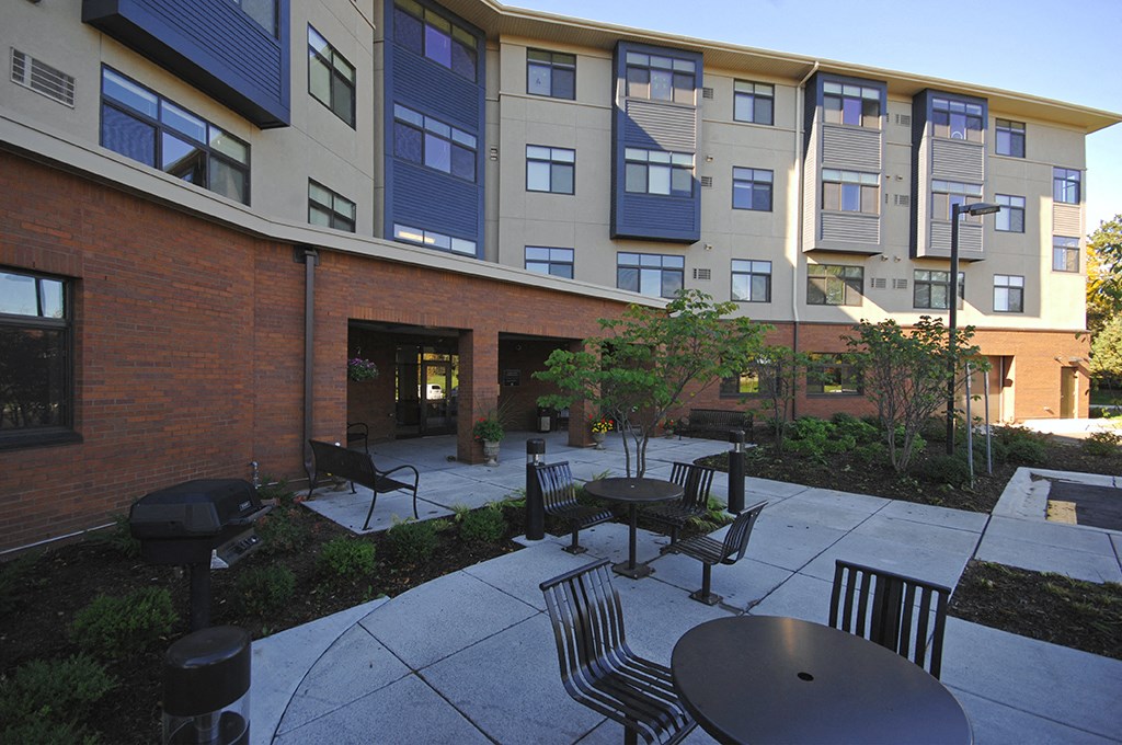 an outdoor courtyard with tables and chairs in front of an apartment building