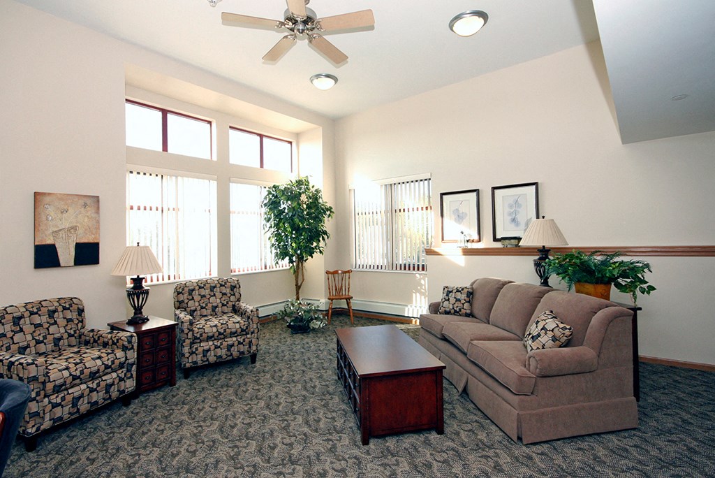 a living room with couches and chairs and a ceiling fan