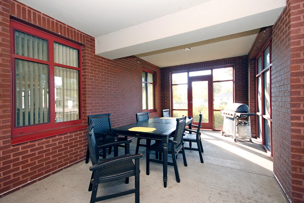 a patio with a table and chairs and a grill