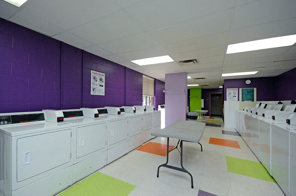 a laundry room with a table and a row of washing machines