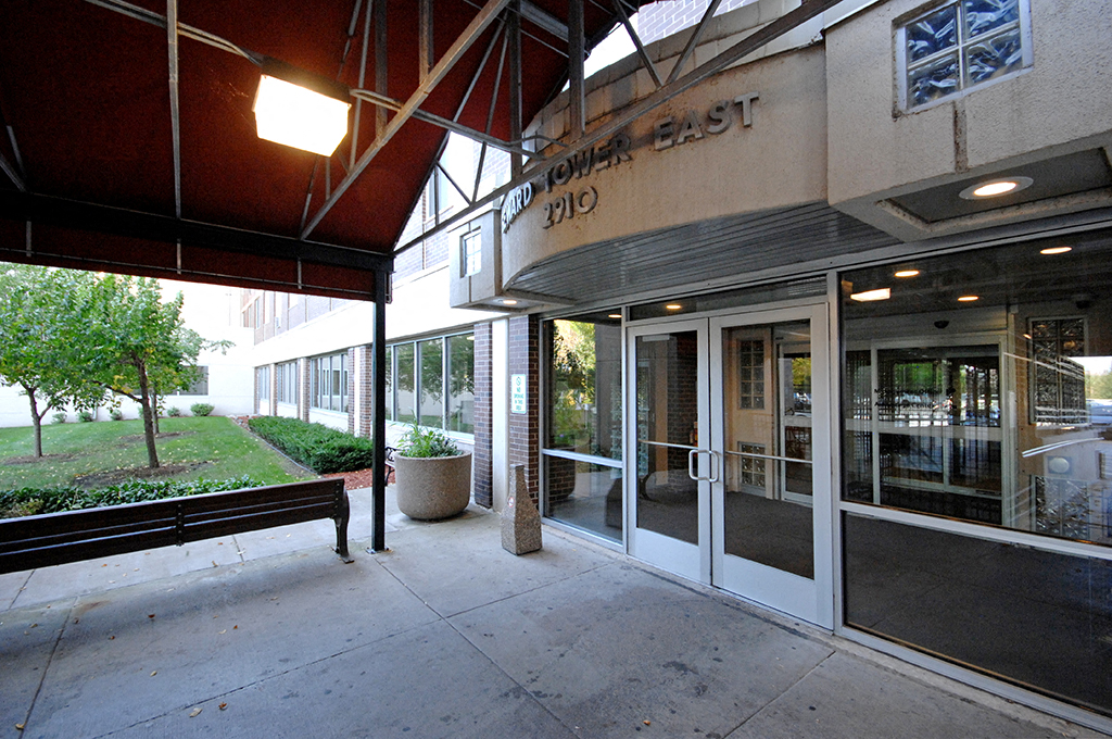 a sidewalk outside of a building with glass doors and a bench