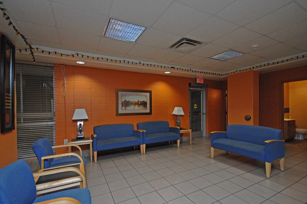 a waiting room with blue chairs and orange walls