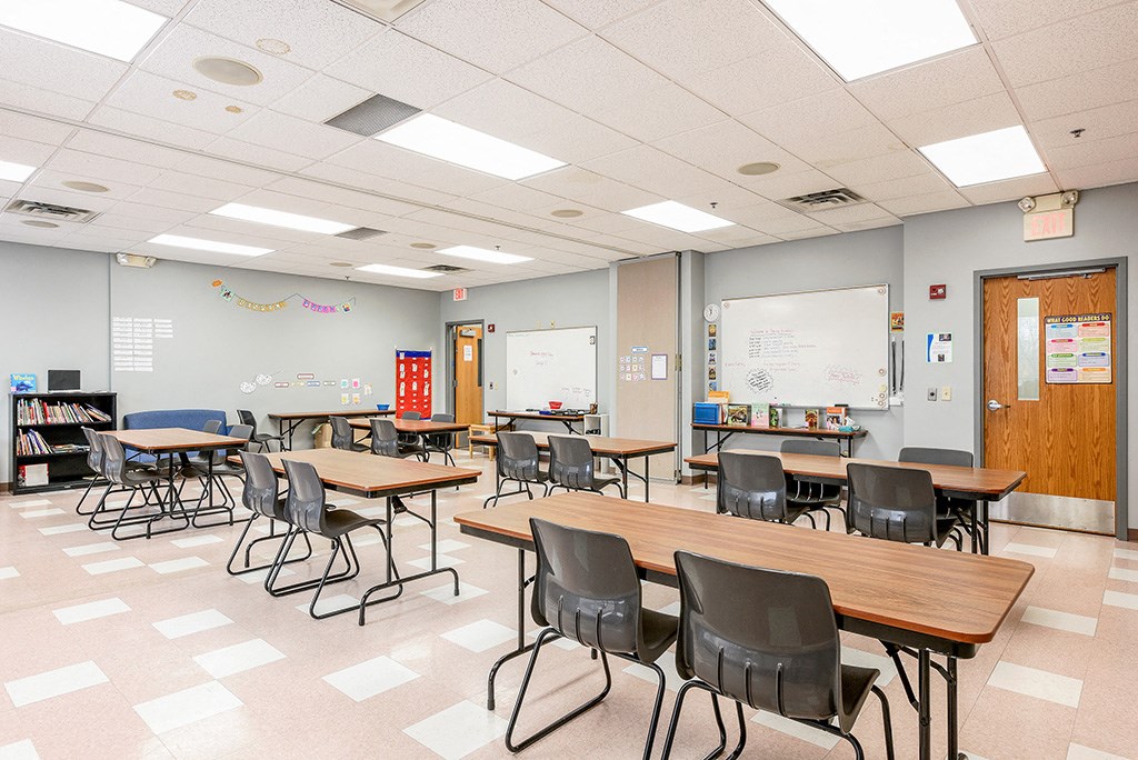 a classroom with tables and chairs and a whiteboard