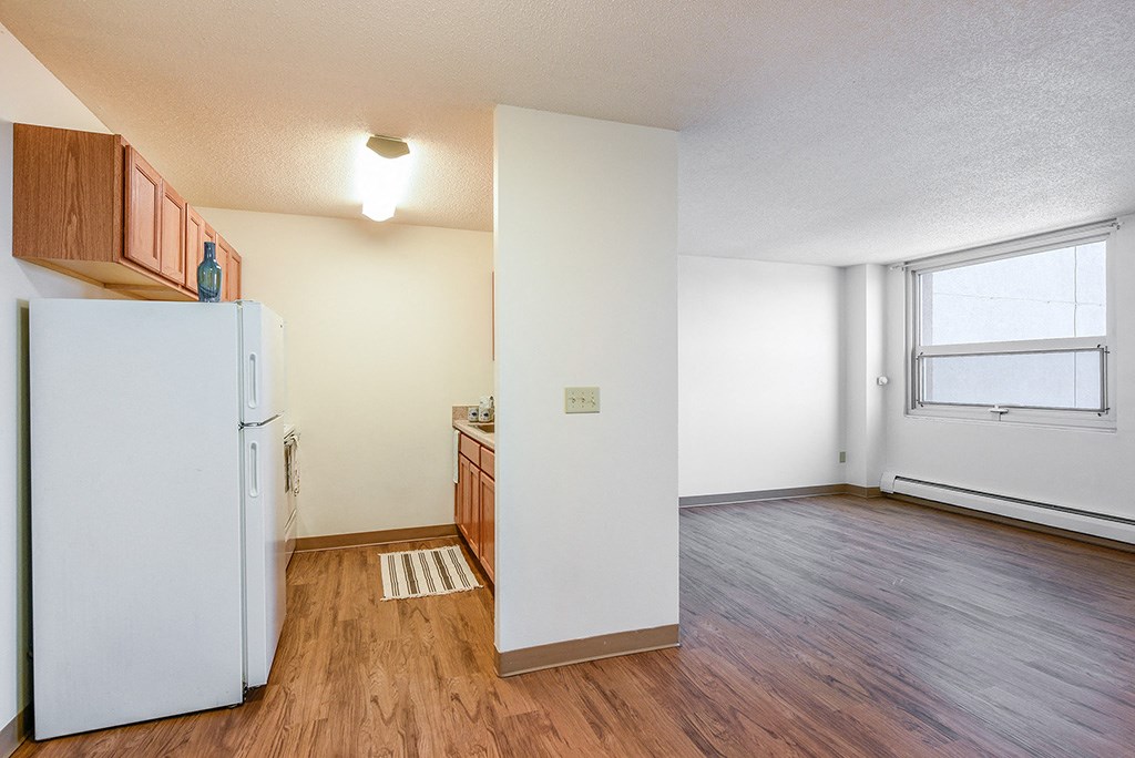 an empty kitchen with a refrigerator and a window