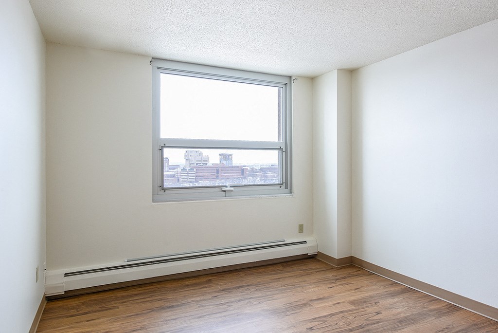 an empty room with a window and wooden floors