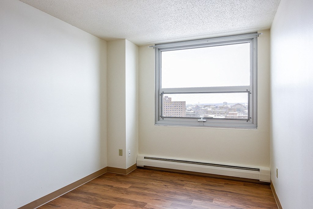 an empty room with a window and wooden floors