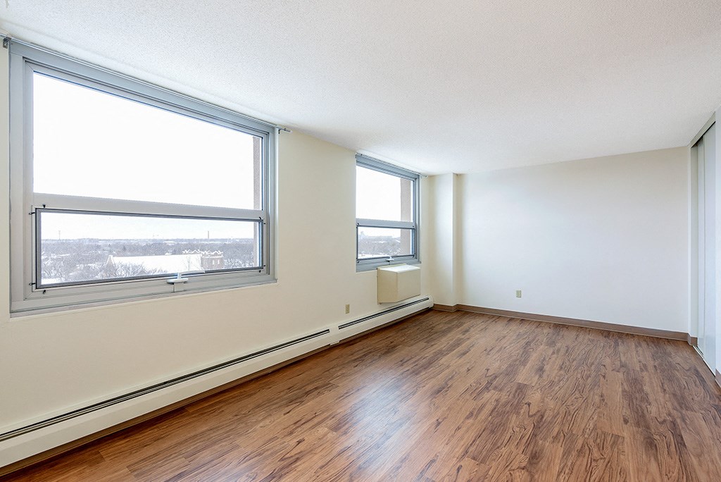 an empty room with wood floors and two windows