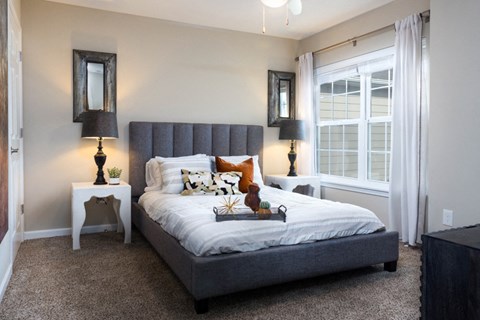 A bedroom with a large bed and two lamps on either side of the bed.