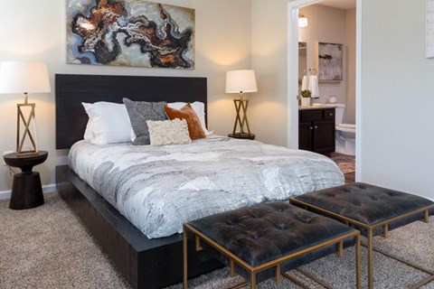 A bedroom with a large bed and a painting on the wall.