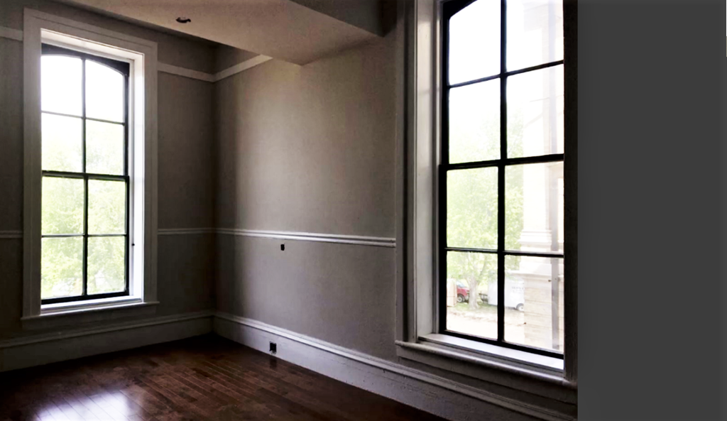 an empty room with large windows and wooden floors