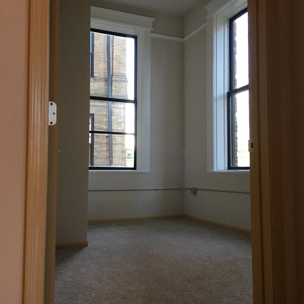 an empty room with two windows and a door